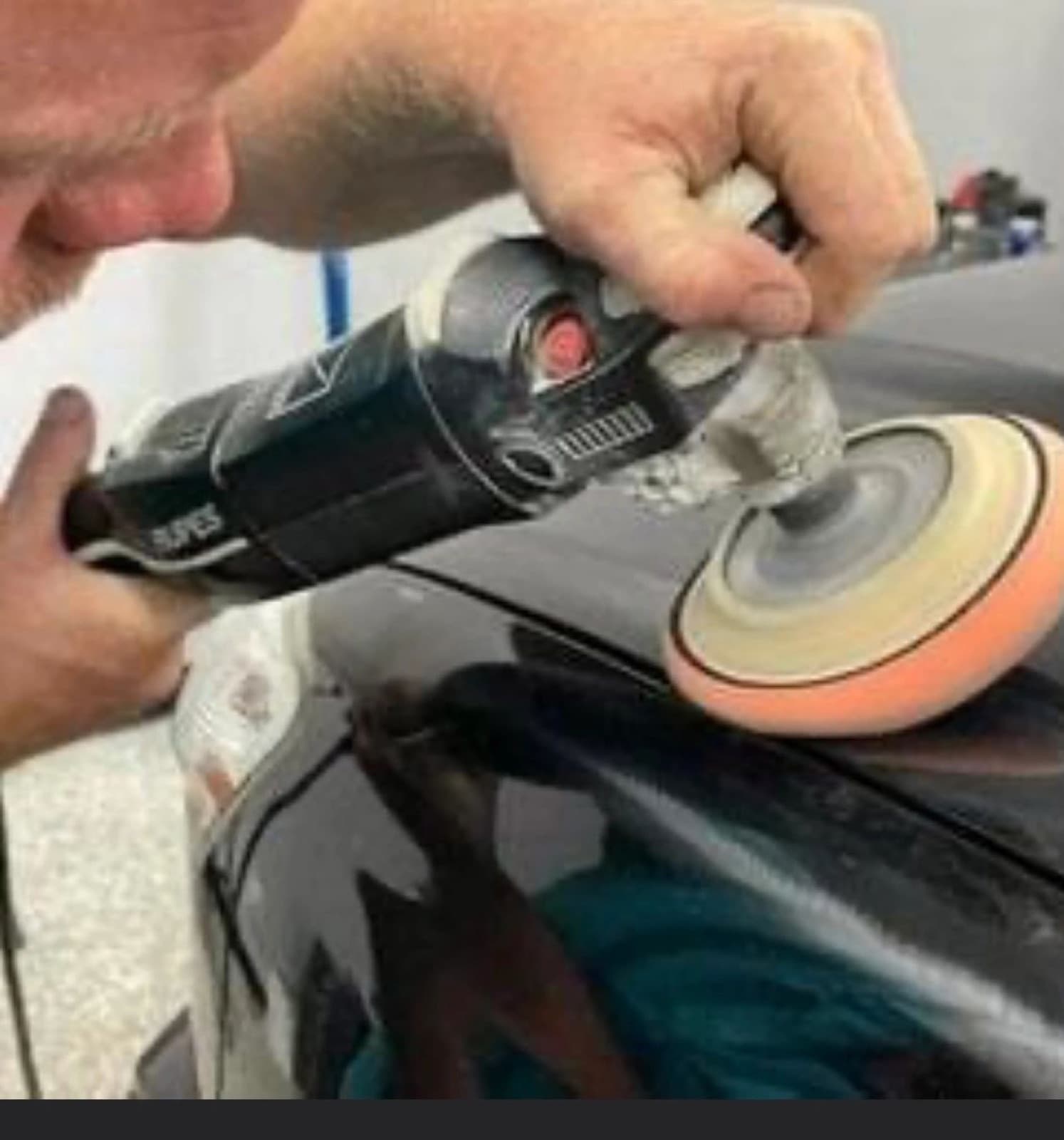 Close-up of a dual-action polisher correcting dark paint